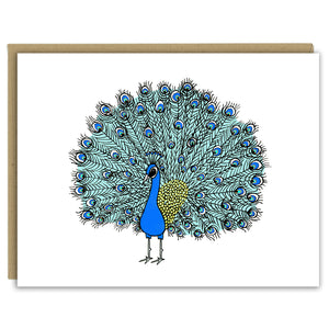 A greeting card with a hand-drawn ink illustration of peacock with its showy tail feathers in full plume. Shown with a Kraft paper envelope on a white background. 