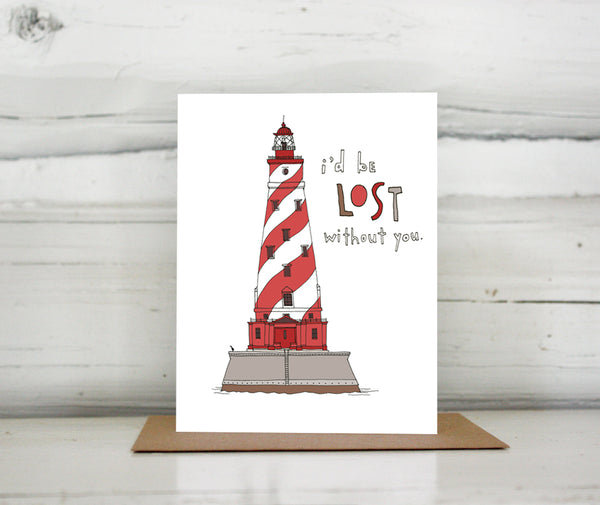 A greeting card showing a hand-drawn illustration of the White Shoals lighthouse in Michigan, a red and white striped lighthouse. The card has a hand-lettered message reading, "I'd be lost without you." Shown standing on a Kraft paper envelope in front of a white-washed log wall. 