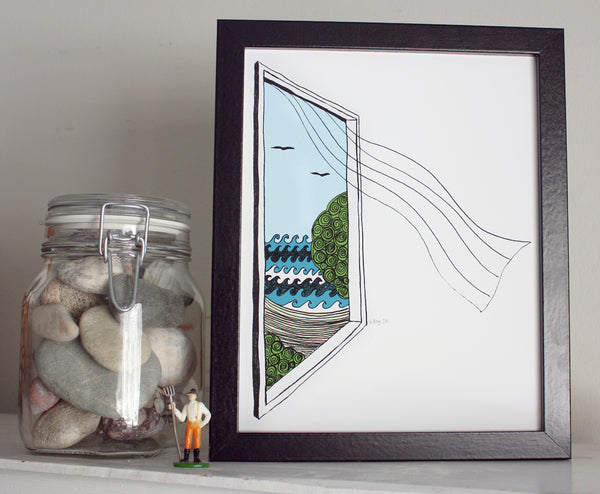 A print of a hand-drawn illustration of a window looking out on ocean waves, a beach and seagulls, a sheer curtain blows in from the window. Shown in a black frame next to a jar of rocks.