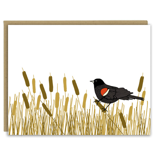 A greeting card showing a hand-drawn illustration of red-winged blackbird resting amongst a swath of cattails. Shown with a Kraft paper envelope on a white background. 