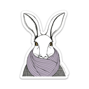 A sticker with a hand-drawn ink illustration of a white rabbit bundled up in a tweed overcoat and purple scarf covering its mouth. Shown on a white background.