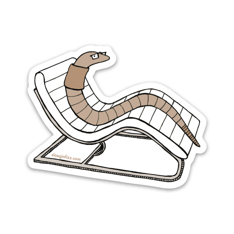 A sticker with a hand-drawn ink illustration of an earthworm reclining on a white mid-century modern lounge chair, seen on a white background. 