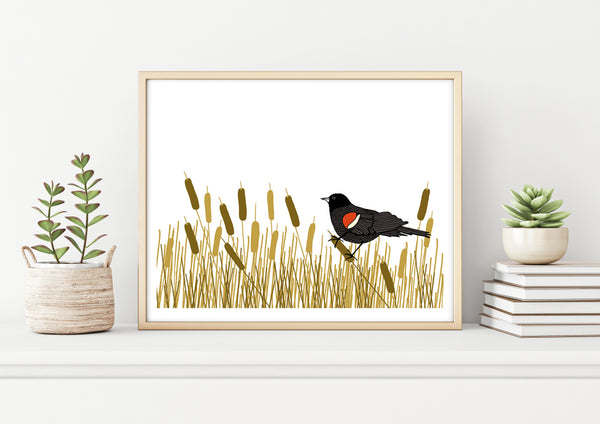 A print of a hand-drawn illustration of red-winged blackbird resting amongst a swath of cattails. Shown in a birch frame on a shelf with two potted plants and a stack of books. 